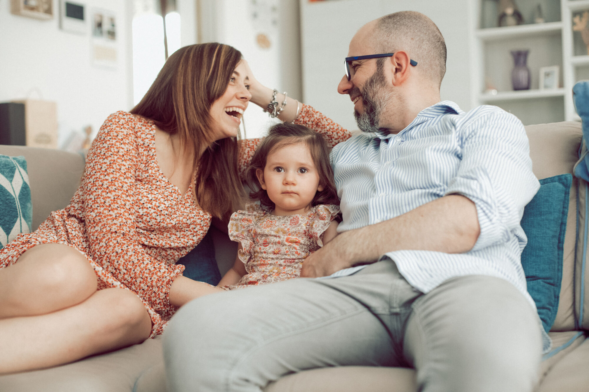 Mamma, papà e bimba sorridenti sul divano di casa