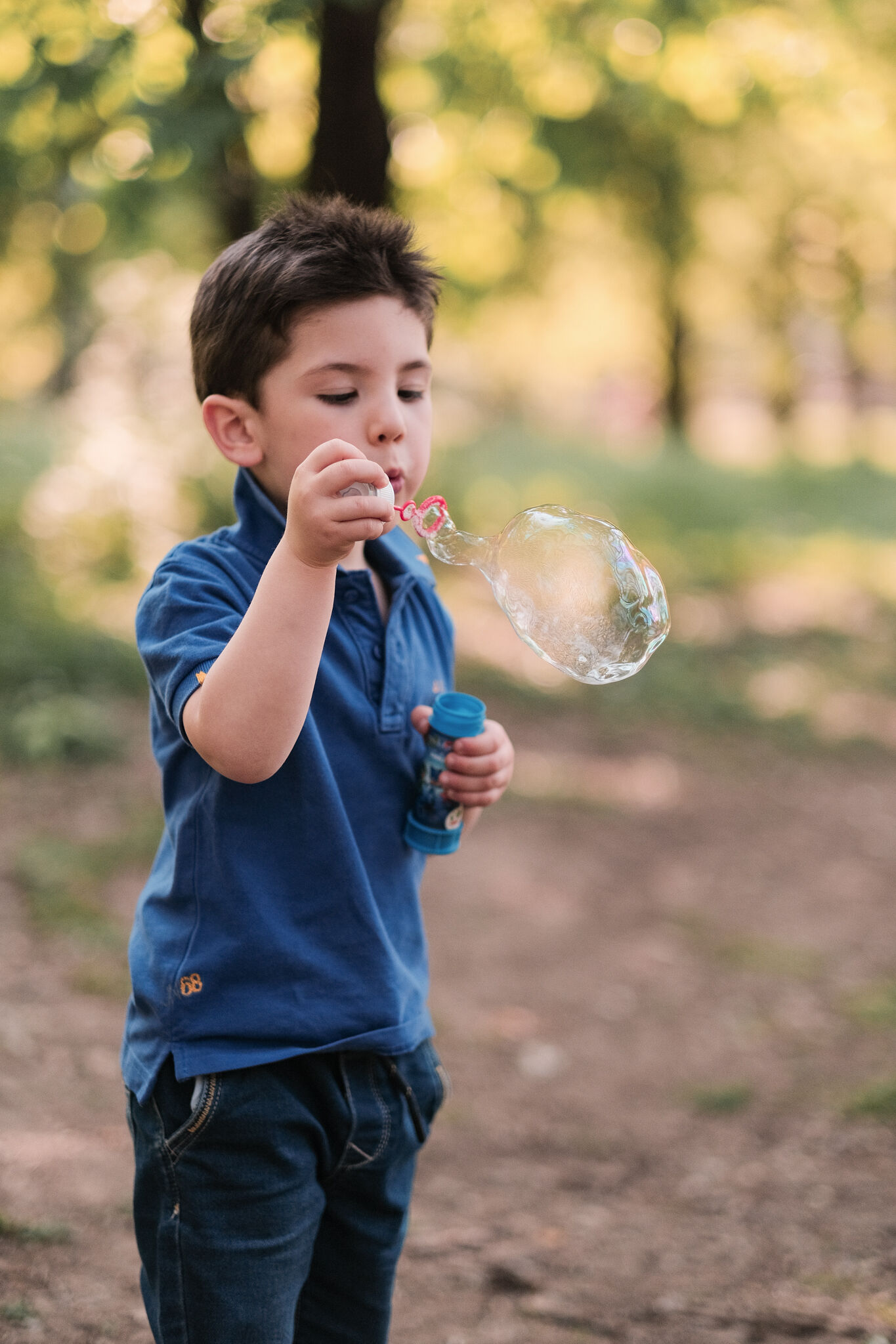 Bambino che soffia una bolla di sapone al parco durante il servizio fotografico