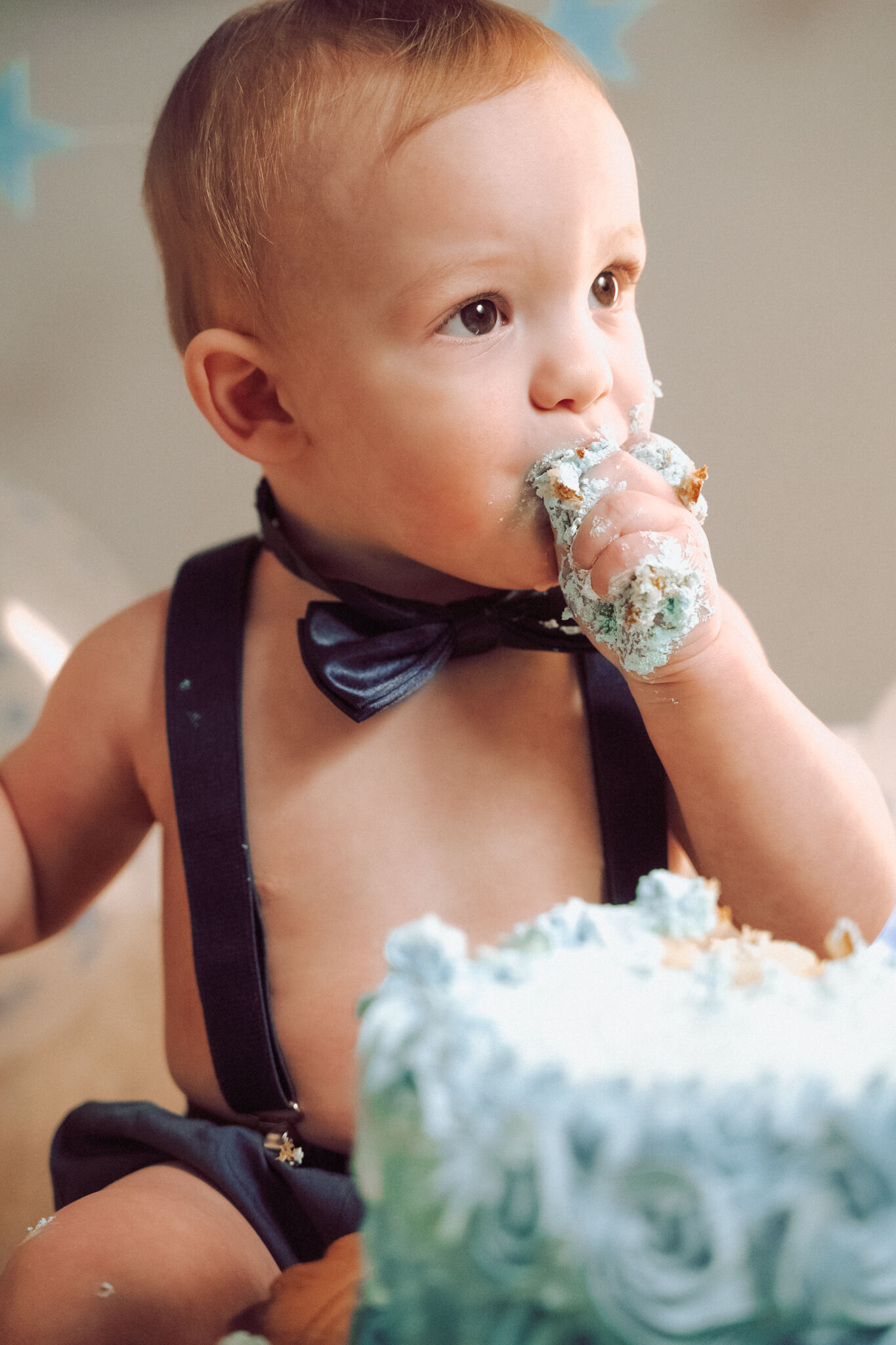 Bambino con papillon che mangia la torta di compleanno con le mani, smash cake in studio