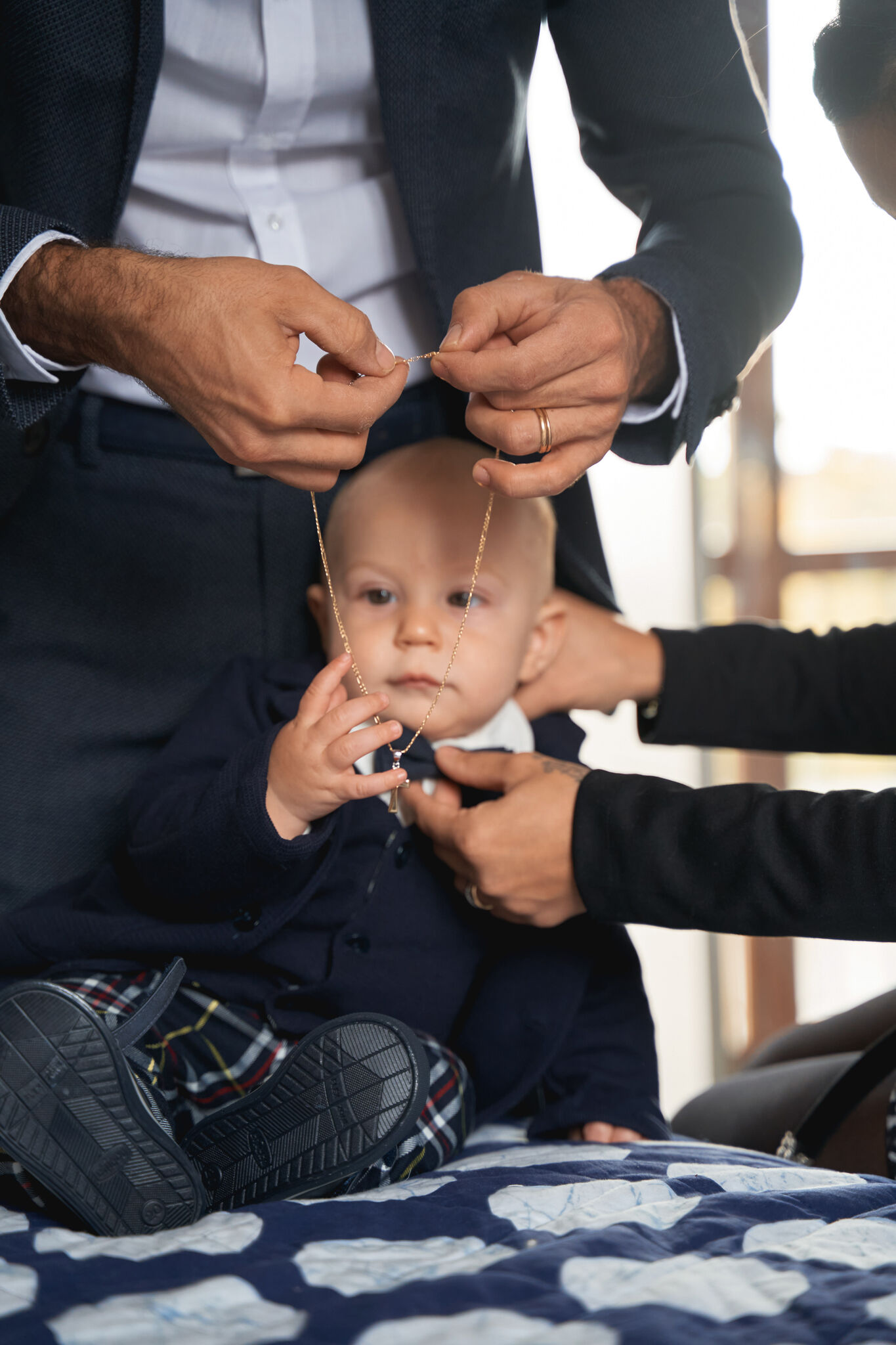 Mani che allacciano il vestitino del bambino prima del battesimo