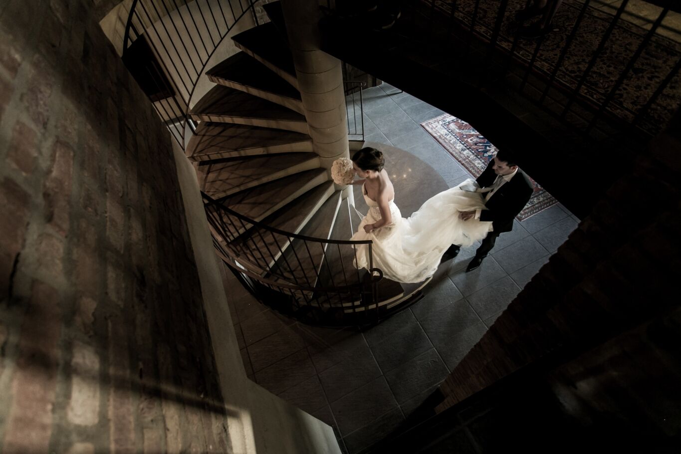 Vista dall'alto di una scala a chiocciola con sposa in abito bianco e sposo, matrimonio reportage