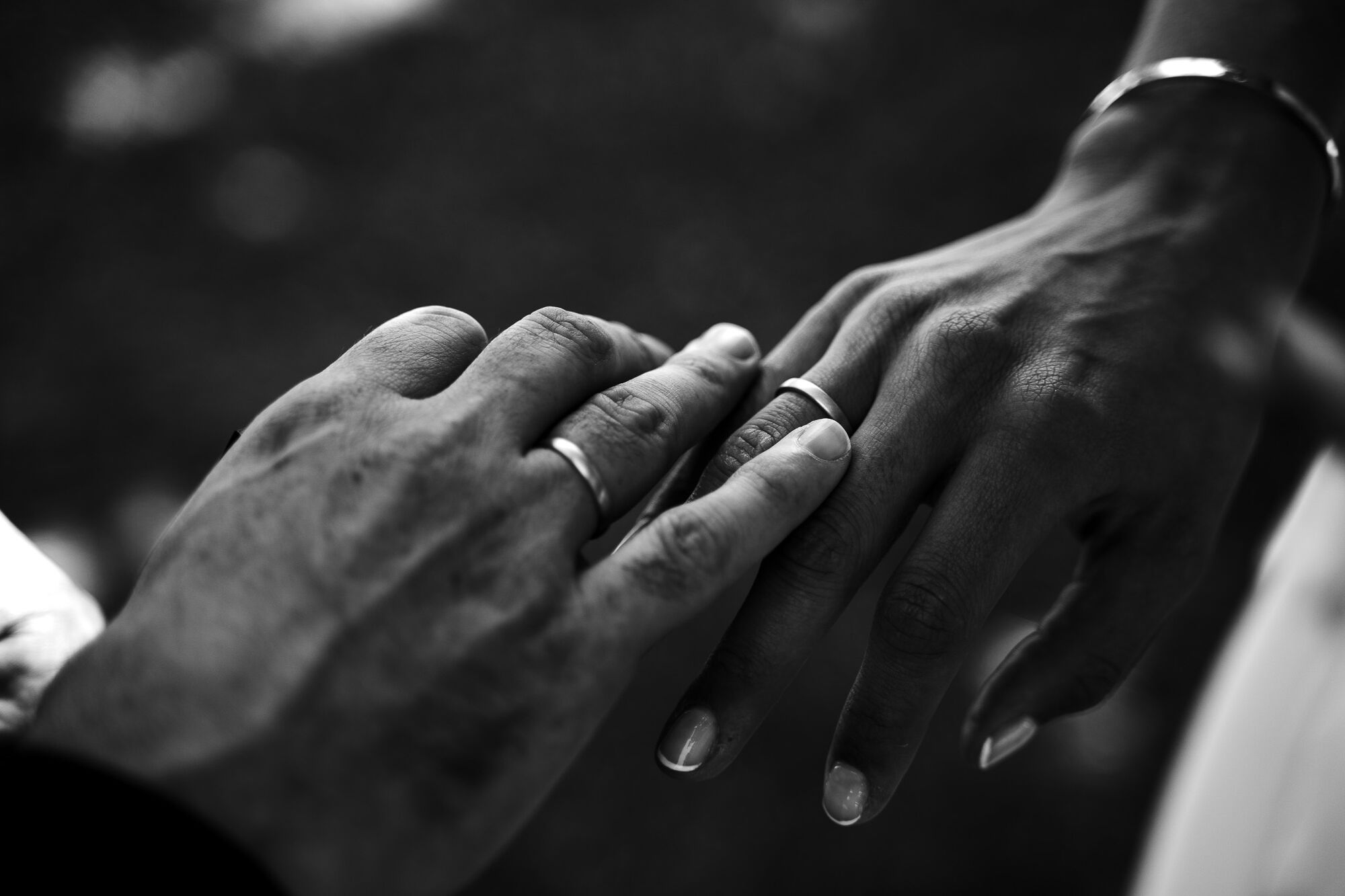 Scambio delle fedi in primo piano, mani degli sposi in bianco e nero, matrimonio reportage